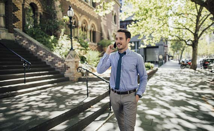 Australasian businesman on commute to work, speaking on mobile phone as he walks