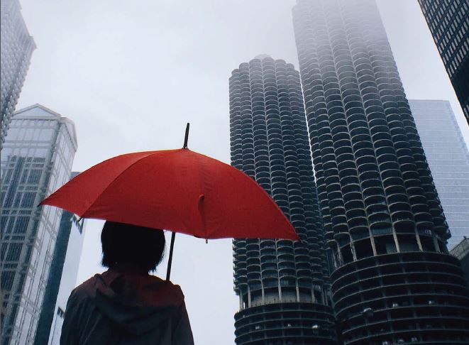 Report cover image of a woman in a city carrying an umbrella surrounded by skyscrapers