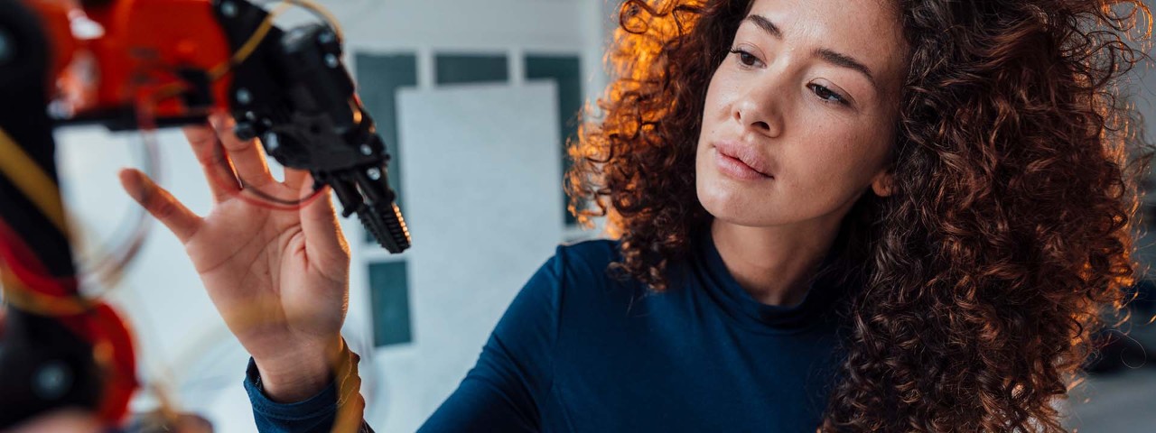 person looking and touching a robotic arm
