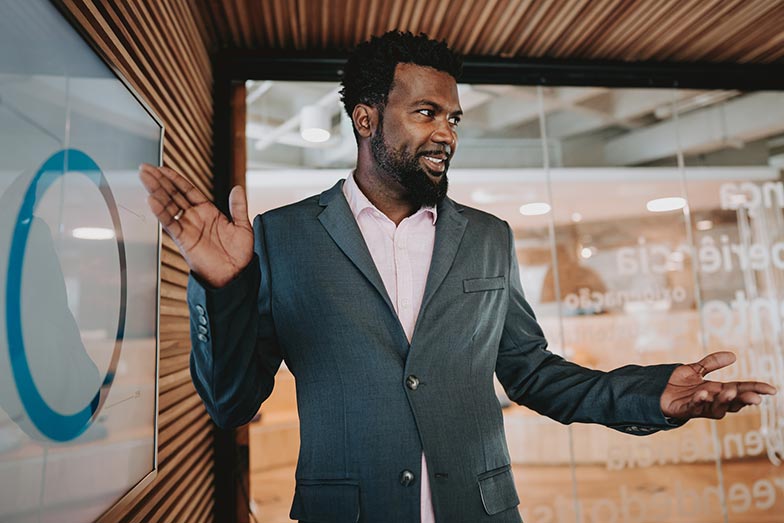 man gesturing at screen with chart in meeting