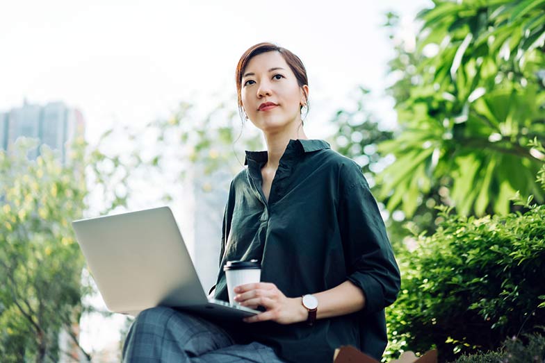 woman sitting outdoors with laptop