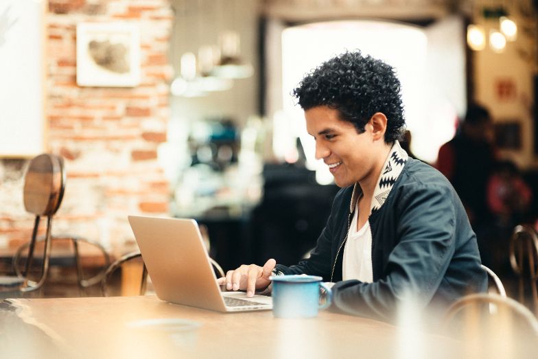 happy young person working on laptop in cafe