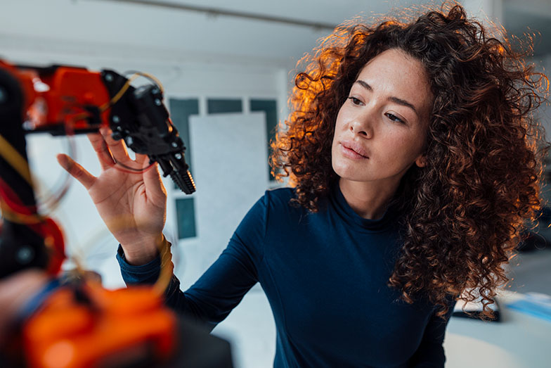 person looking and touching a robotic arm