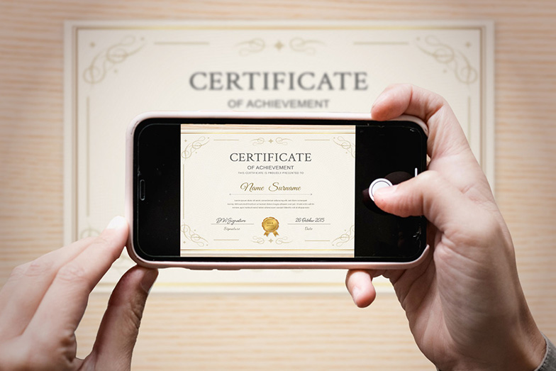 person taking a photo of a certificate on a smart phone; the certificate is clearly framed on screen and all the certificate's text is readable