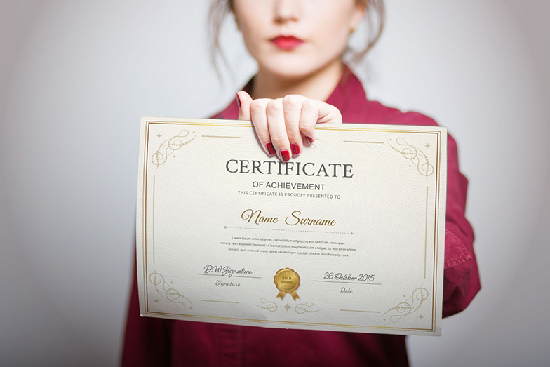 person holding a certificate up; the certificate's text is not clearly visible and the person is visible in the photo