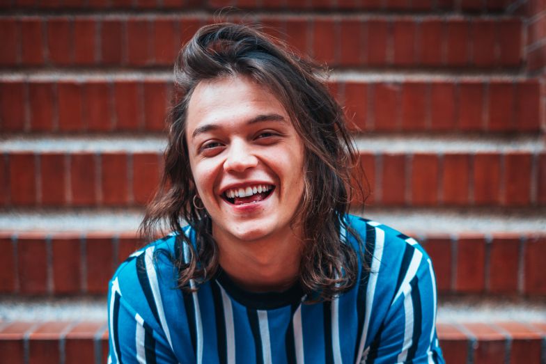 young person laughing sitting on red brick steps