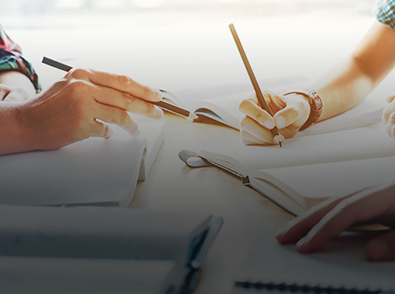 people using pens to write in books