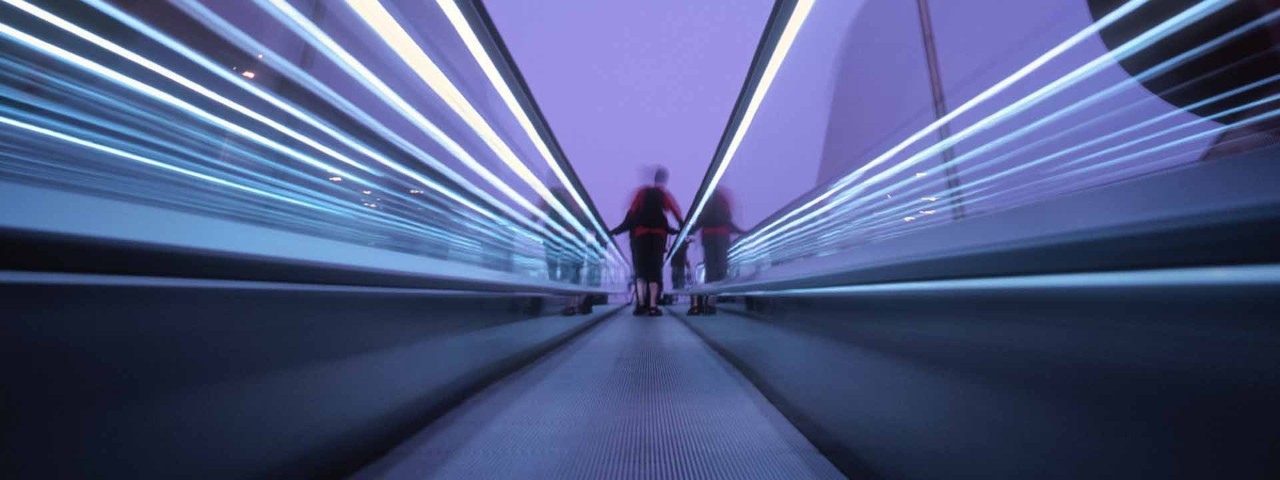 Dark purple abstact image of person moving down an escalator