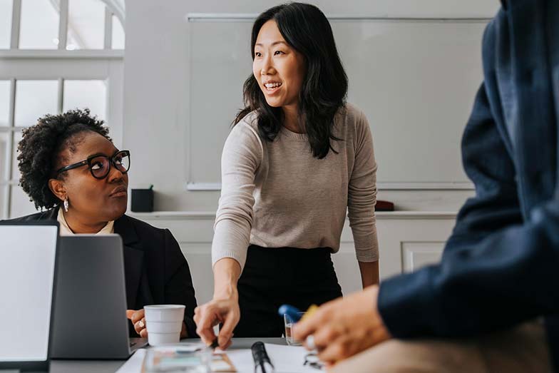 woman standing at a desk with two other persons