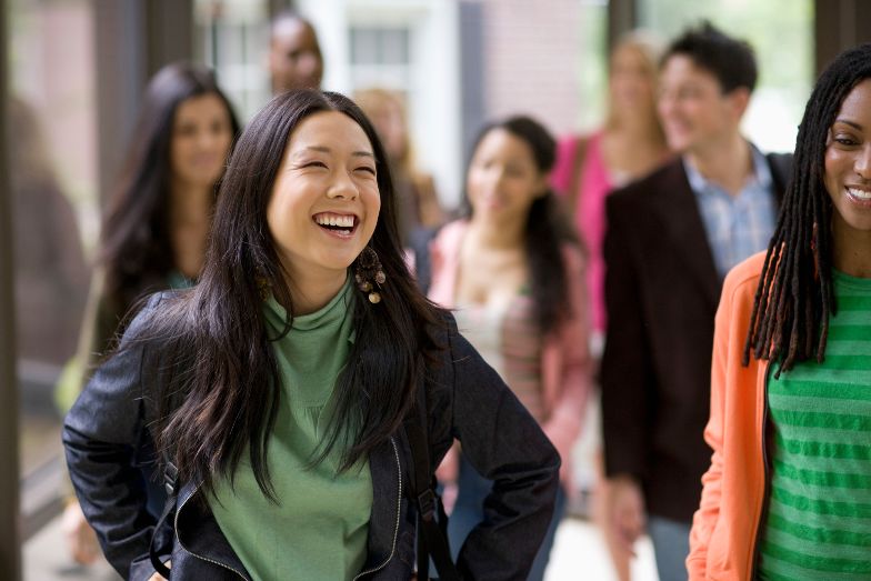 happy student walking down hallway with other students in the background