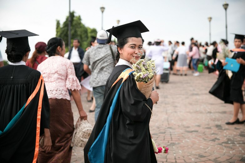Graduate in academic dress holding bouquet