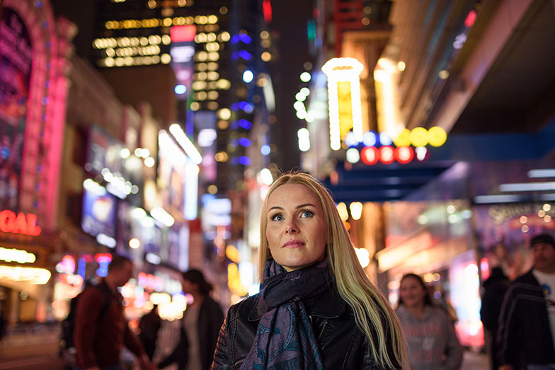 person in brightly lit city at night