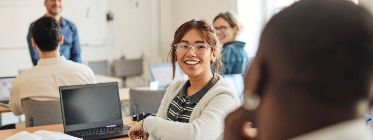 happy student in classroom with laptop