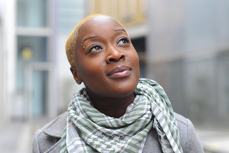 Person smiling in urban setting looking skywards