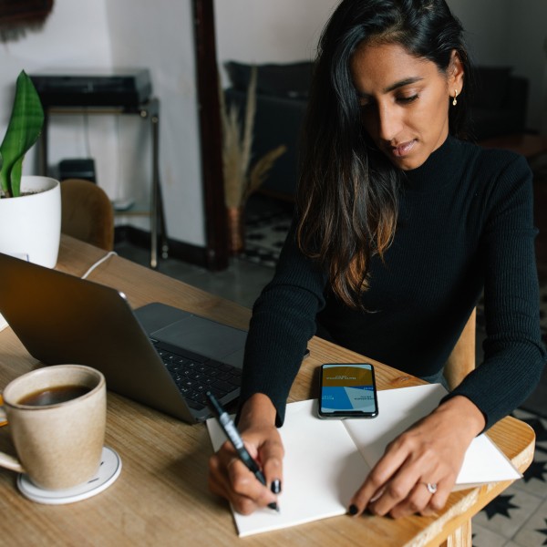 YOUNG WOMAN USING LAPTOP ON TABLE AT HOME