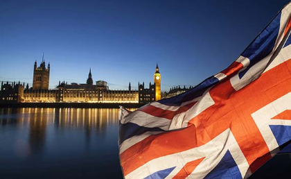 Union flag of the United Kingdom with the UK parliament in the background at night