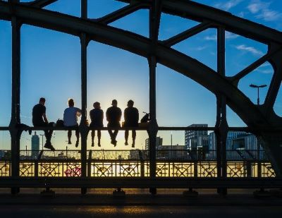 Image of a group of people sitting by a bridge