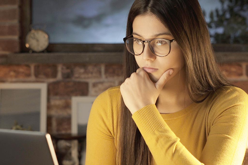 Young woman in yellow jumper working at a laptop
