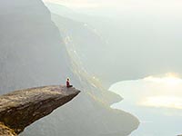 Person meditating on a cliff edge with stunning visibility over the world below