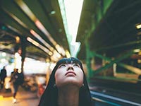 Woman in a busy city environment, looking to the sky