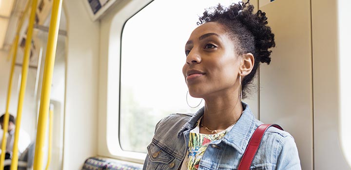 Young woman on a train, looking ahead with a smile on her face