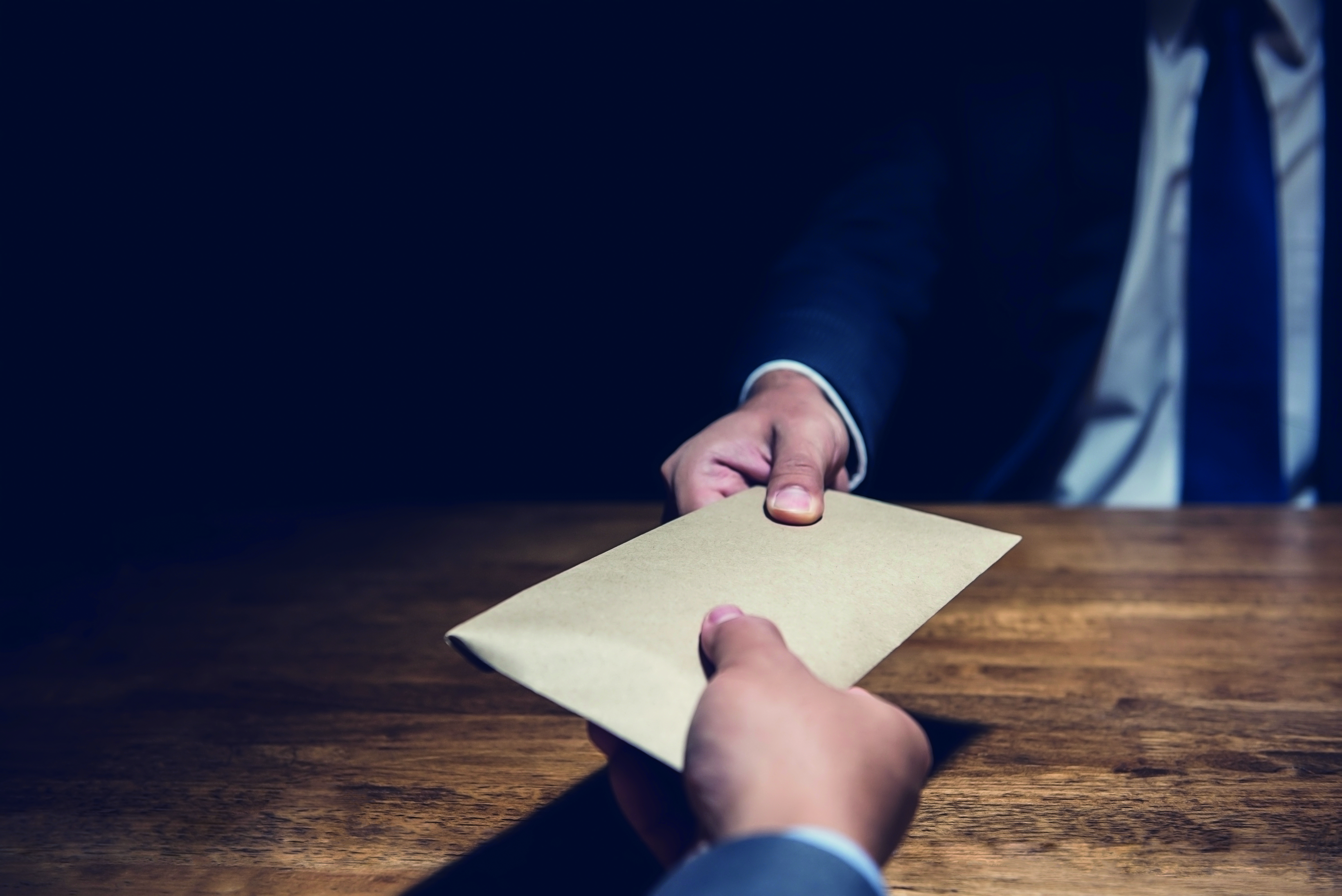 Cover image of the report featuring a man in a suit giving an unlabelled document to someone sitting across the table 