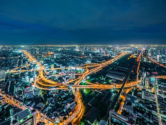 Image a smart city at night with lit up buildings and a number of light trails that illustrates business models of the future