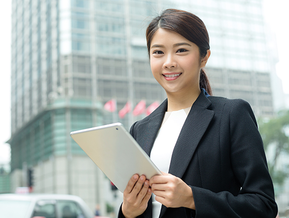 Image of a young Asian professional holding a mobile tablet and smiling