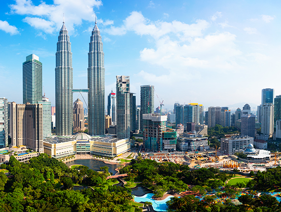 Picture of the capital city of Malaysia, Kuala Lumpur skyline with skyscrapers in the background and a resort in the foreground surrounded by trees