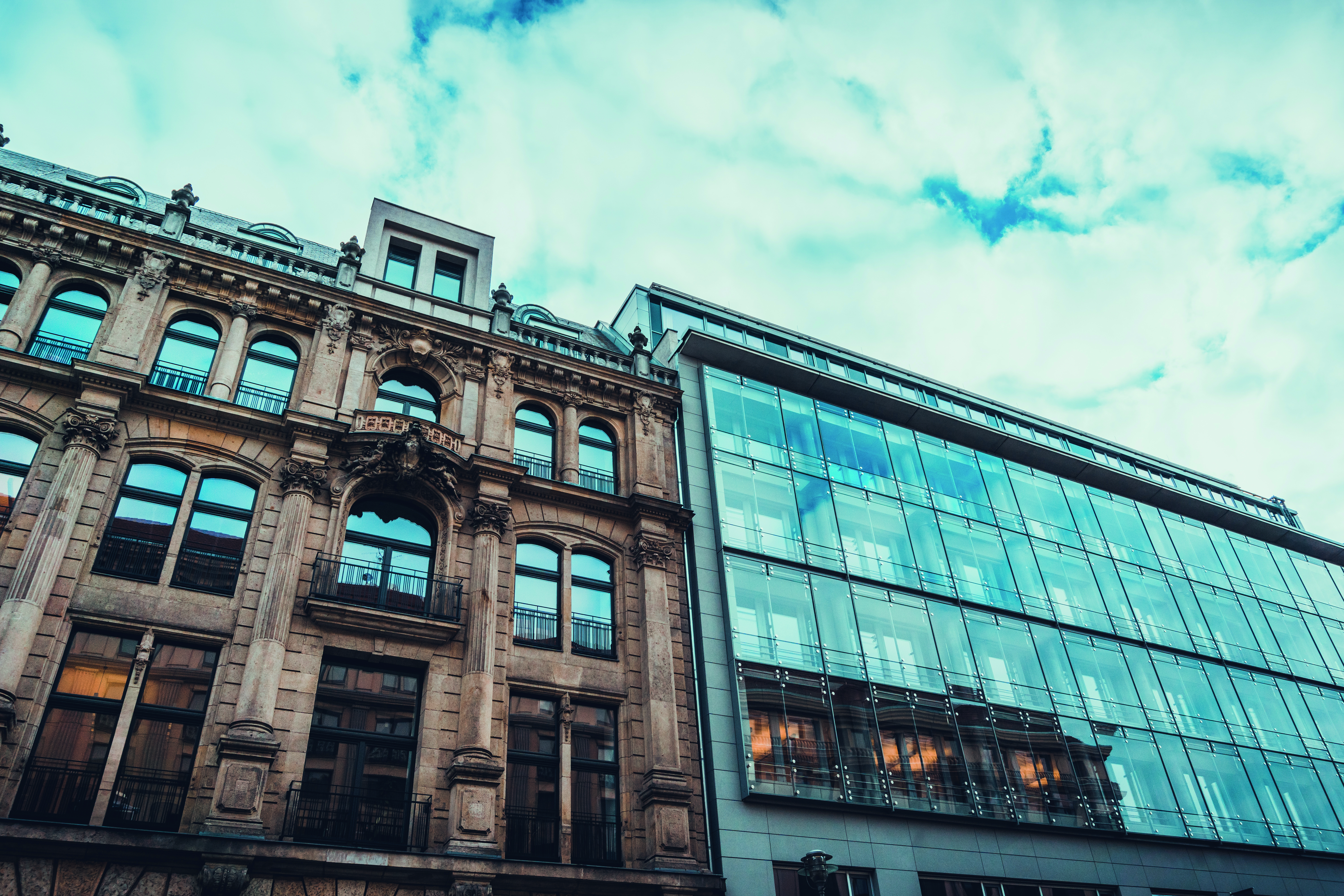 An image of an old historical stone building next to a modern mostly all glass building