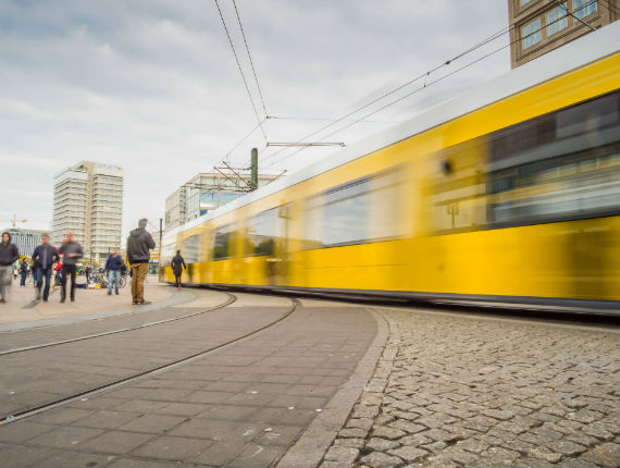 Image of a yellow tram in motion captured out of focus with some people standing