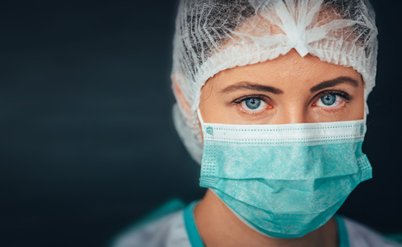 Image of a hospital worker wearing protective equipment, facemask, hair covering and gown 