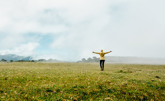 Image on the cover of the report of a person in a raincoat dancing in an empty field in the rain. 