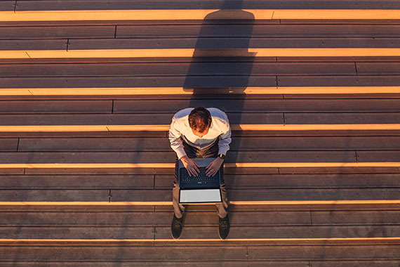 Image on the cover of the report of a man sitting ont he steps of a large building.