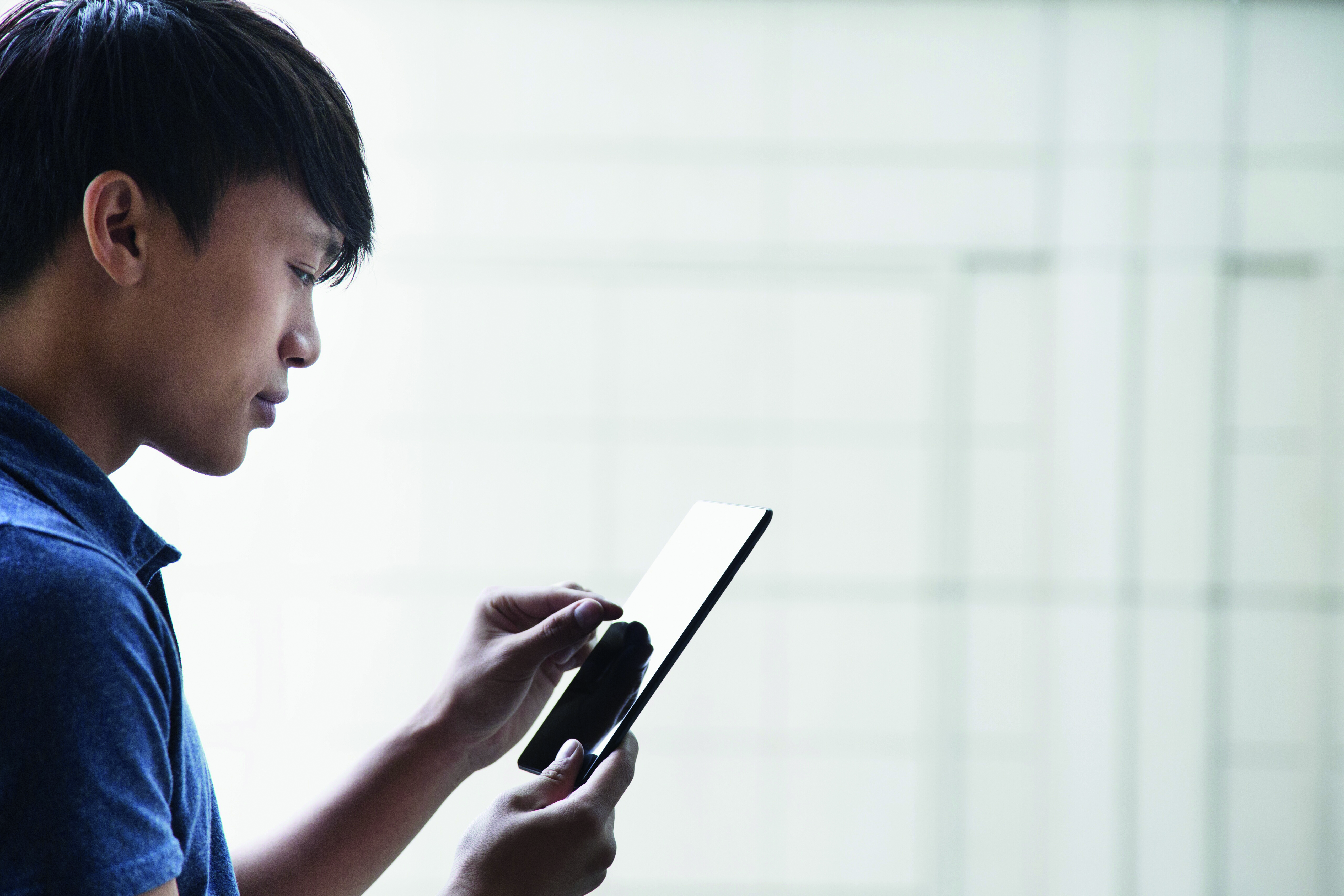 The cover image of the report, which depicts a young man looking at content on his mobile/tablet. 