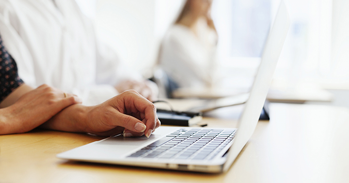 Cropped image of student with laptop in classroom