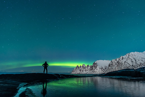 Image of an explorer viewing aurora borealis in a nordic landscape that is on the cover of the report.