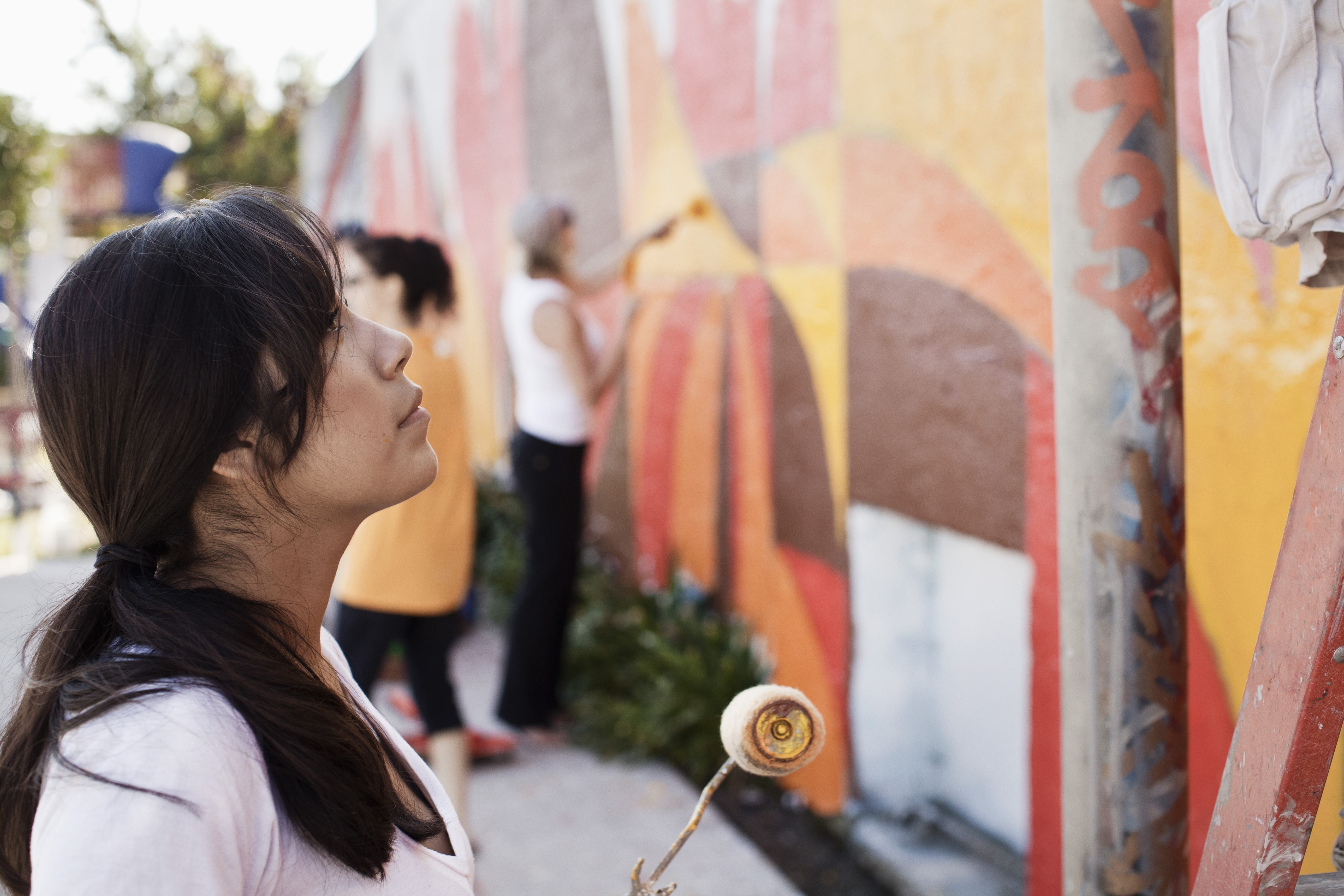 Image of a woman holding paint roller and staring at painted wall. Image is on the front of the report.
