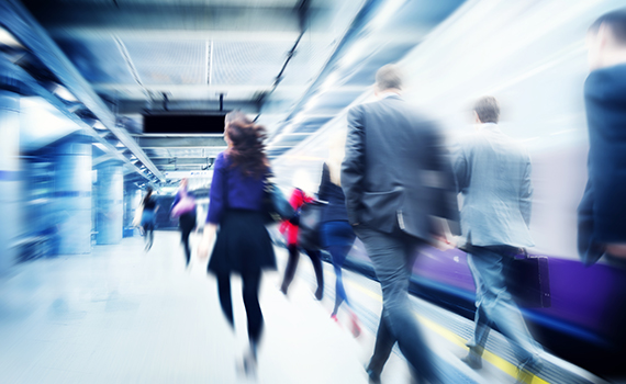 Image of people walking on a train station platform, captured as slightly blurred to illustrate the article topic of the shadow economy