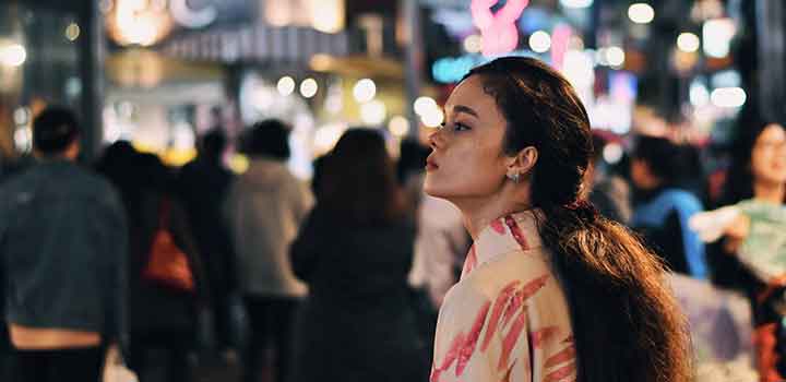 Woman in a busy city centre street at night, looking to the left