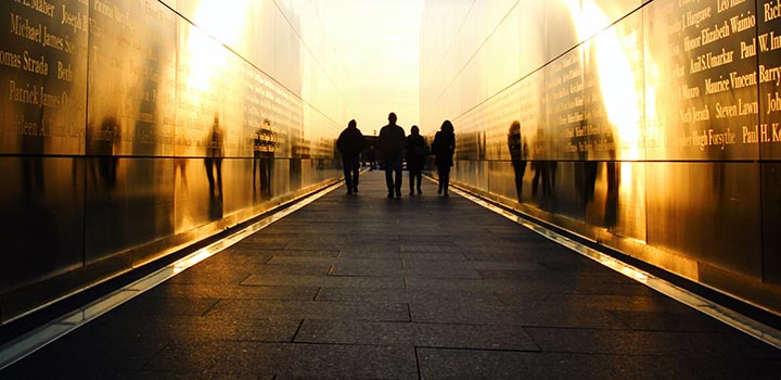 A group of four people in silhouette, walking towards a sunset in an urban setting