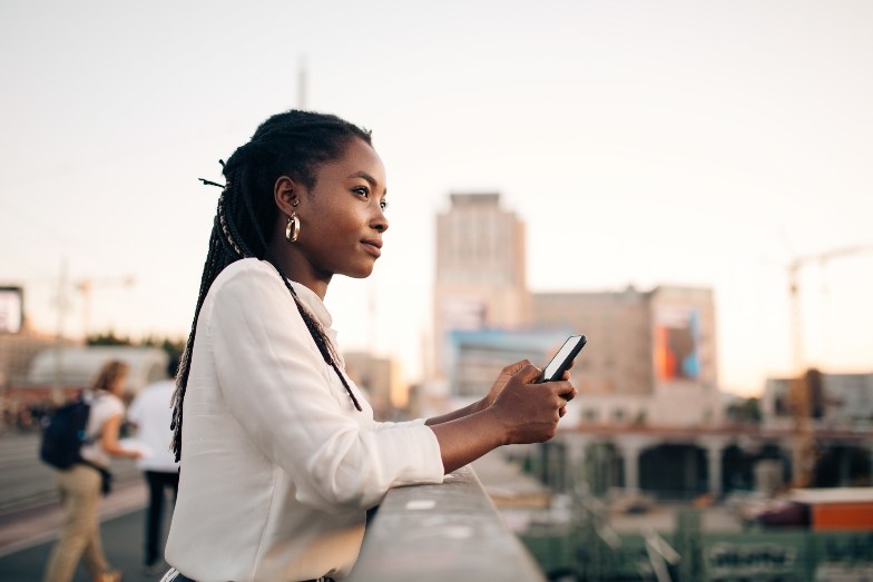 young person with mobile on balcony in city