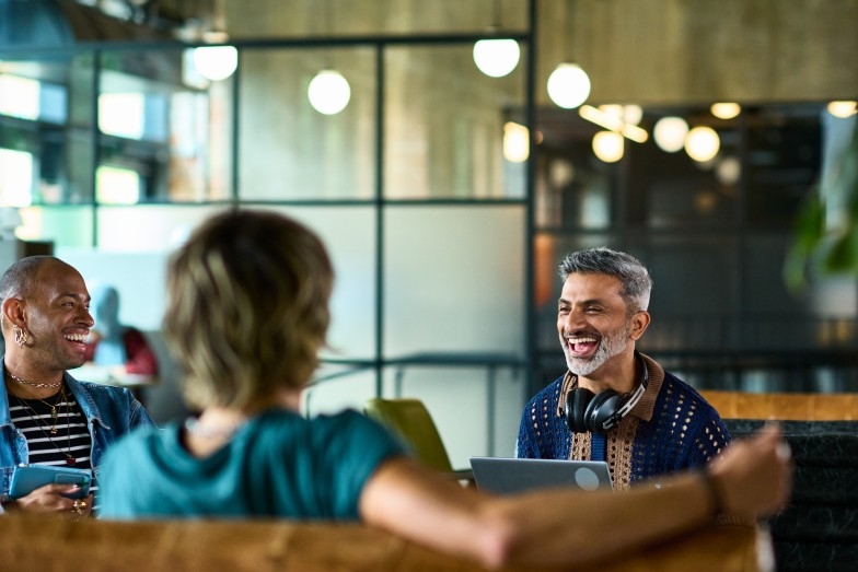 happy person wearing headphones laughing with two other people
