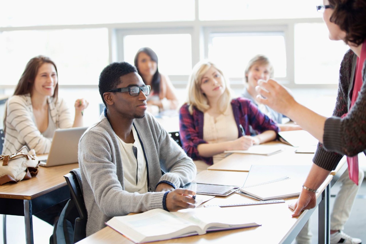 happy students in a classroom listening to teacher