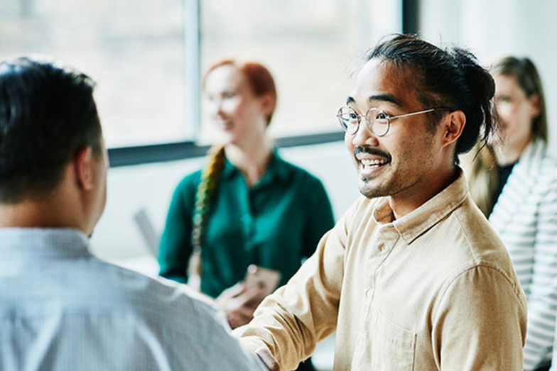 persons shaking hands and smiling in business meeting