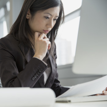 22 Feb 2014 --- Businesswoman reviewing paperwork at desk --- Image by Â© Hero Images/Corbis