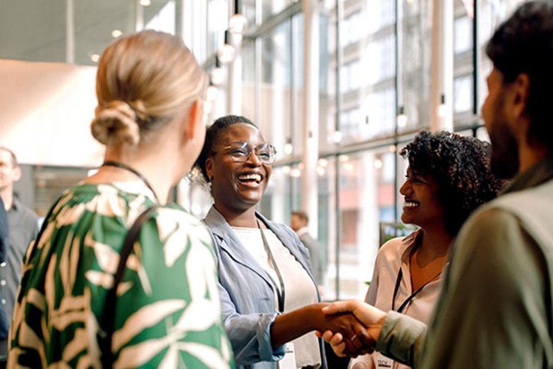 woman smiling and shaking hands at an event