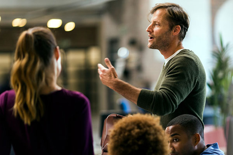 lecturer at event gesturing with hand in front of audience