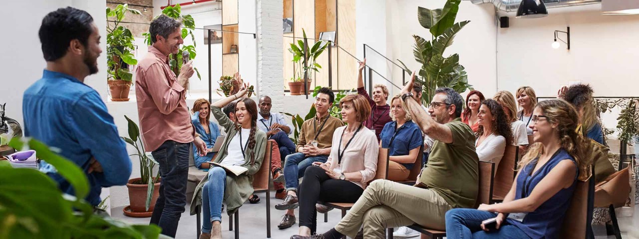 person standing and speaking to an audience at a conference