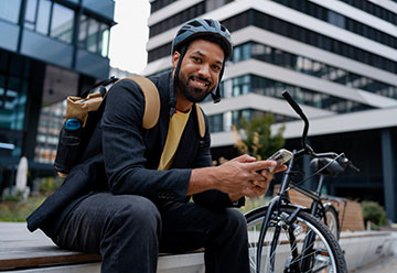 young person sitting on steps with bike in city